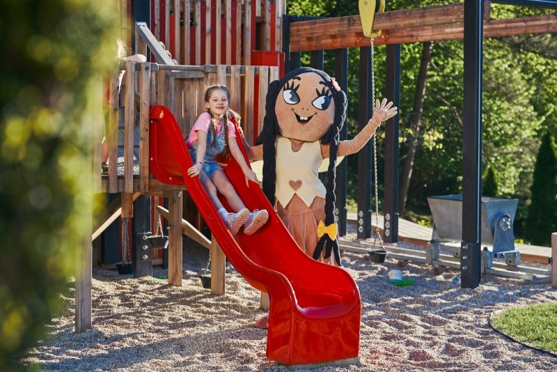 dievčatko s maskotom na šmykľavke