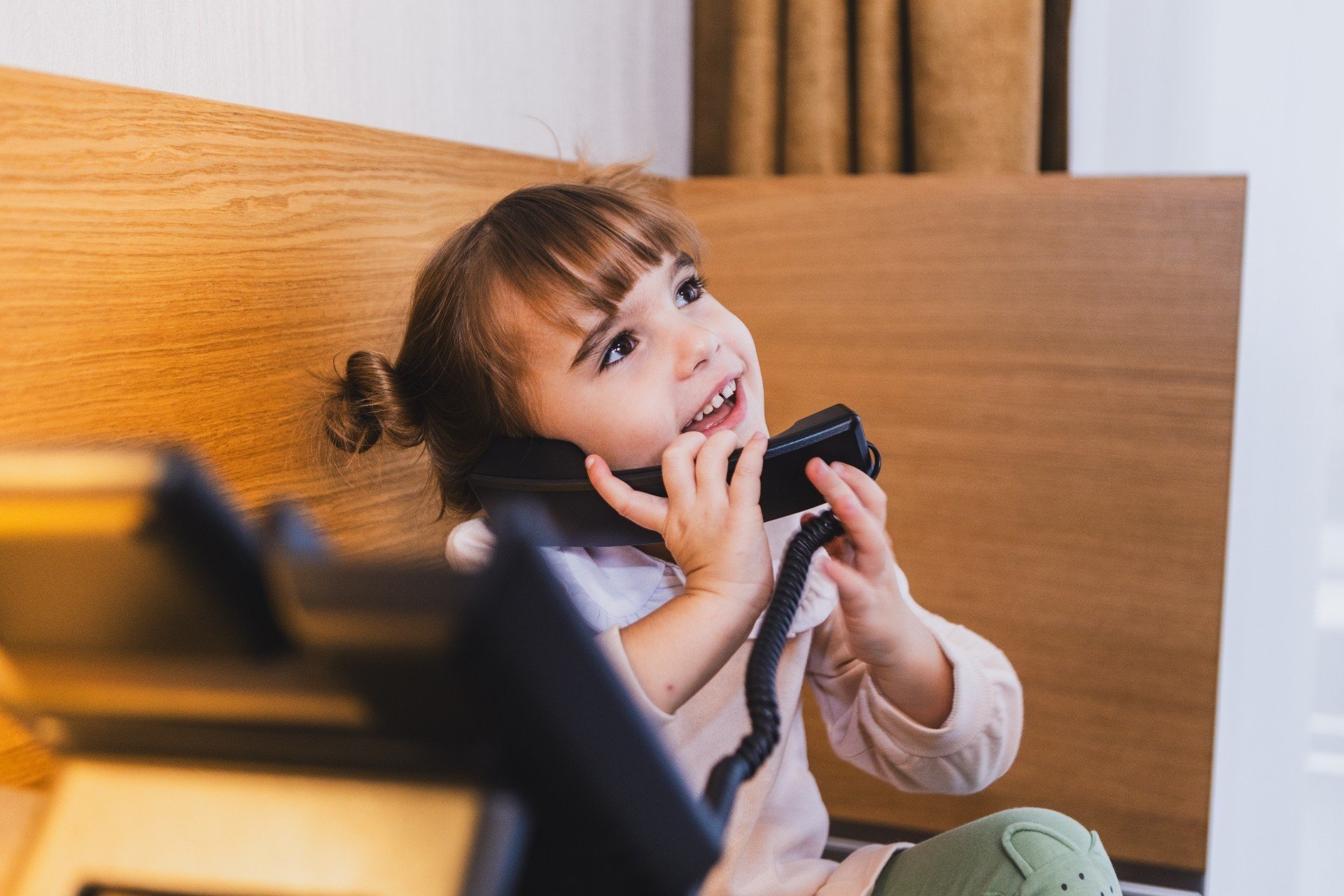 Dievčatko telefonuje v hotelovej izbe